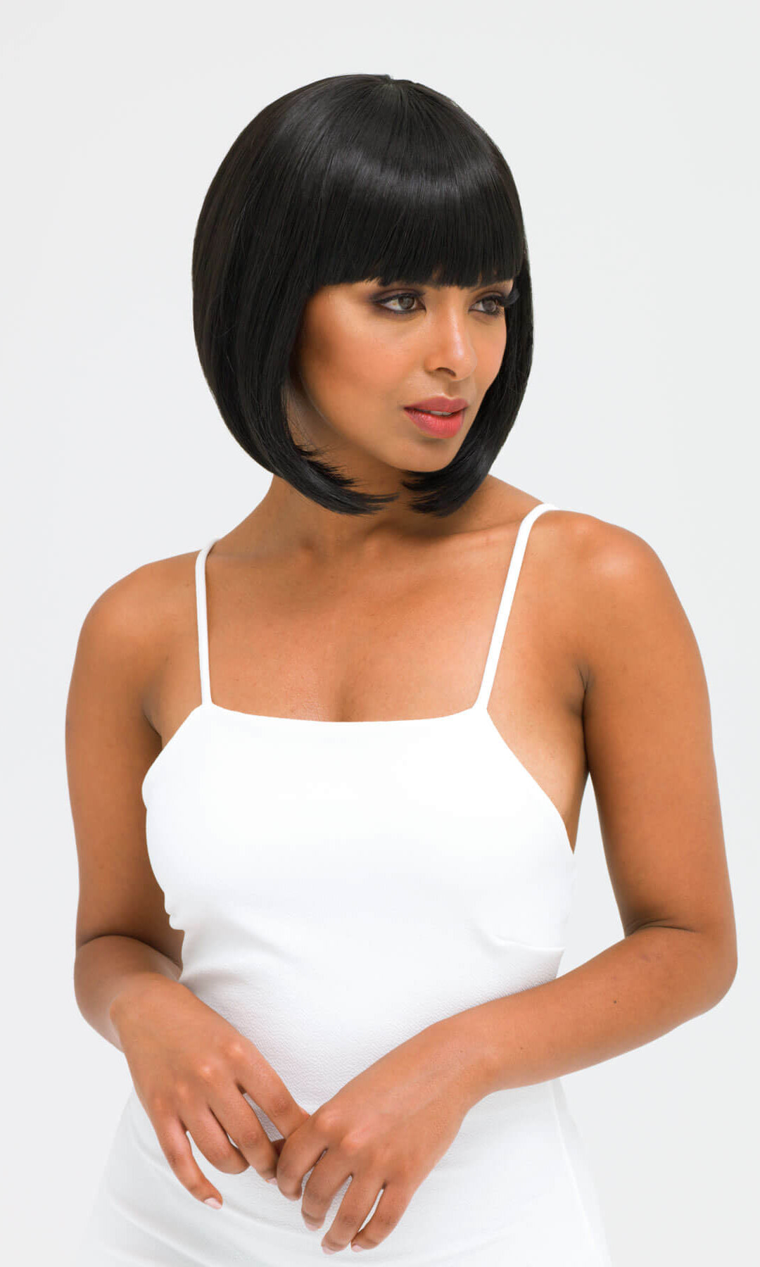 Woman wearing a white dress with a plain background. Black inverted bob wig: Chloe