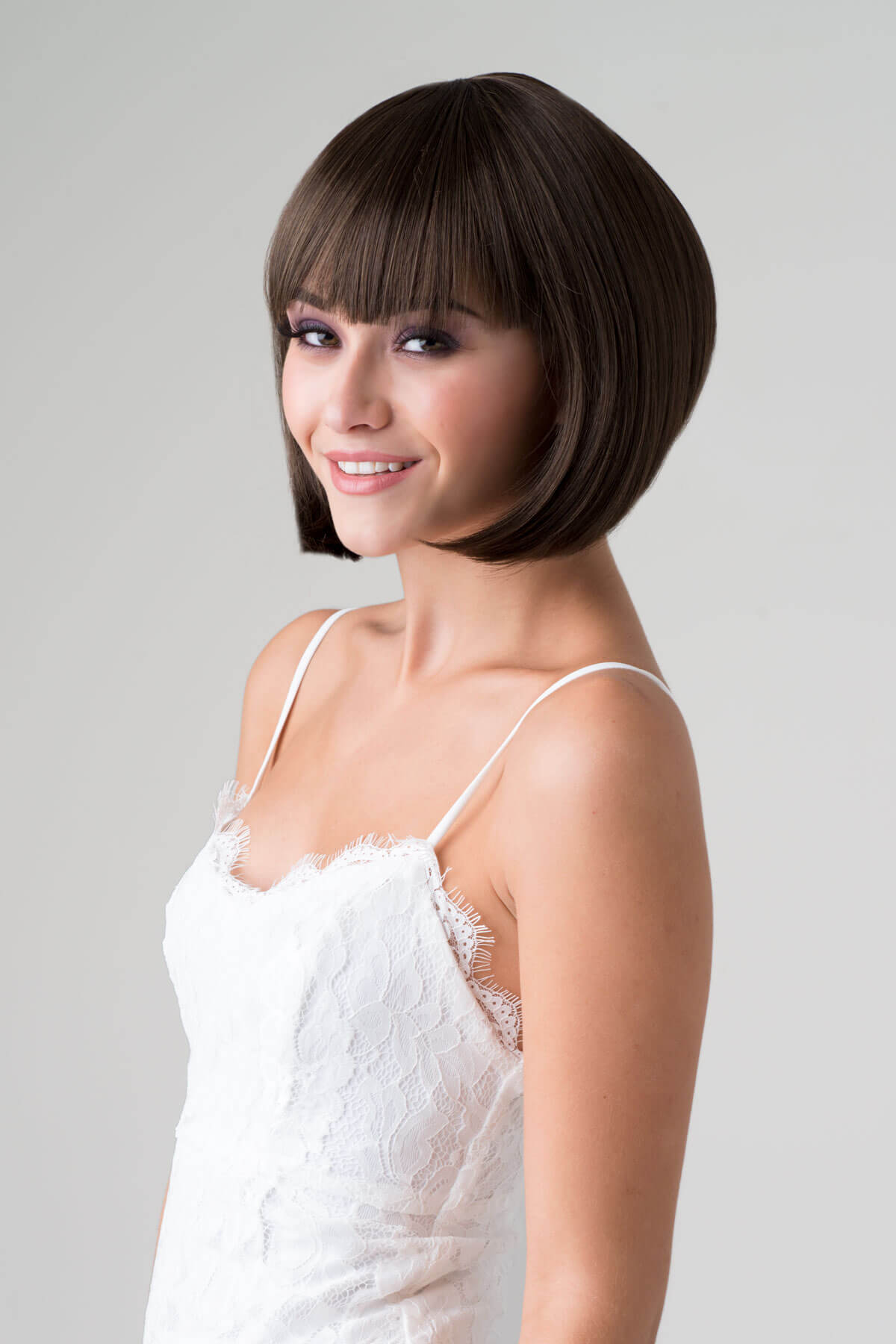 Woman with a stylish haircut wearing a white top against a plain background. Brown inverted bob wig: Colettechestnut brown 8
