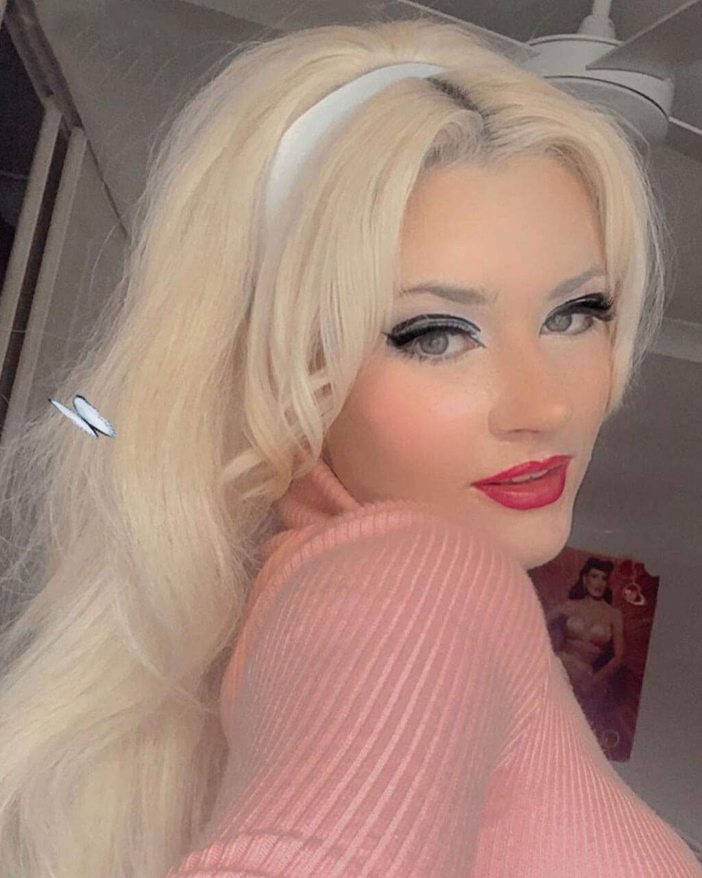 Person with blonde wig and pink sweater in a room. High crown long, wavy half wig and volume ring: Bardot blonde 613