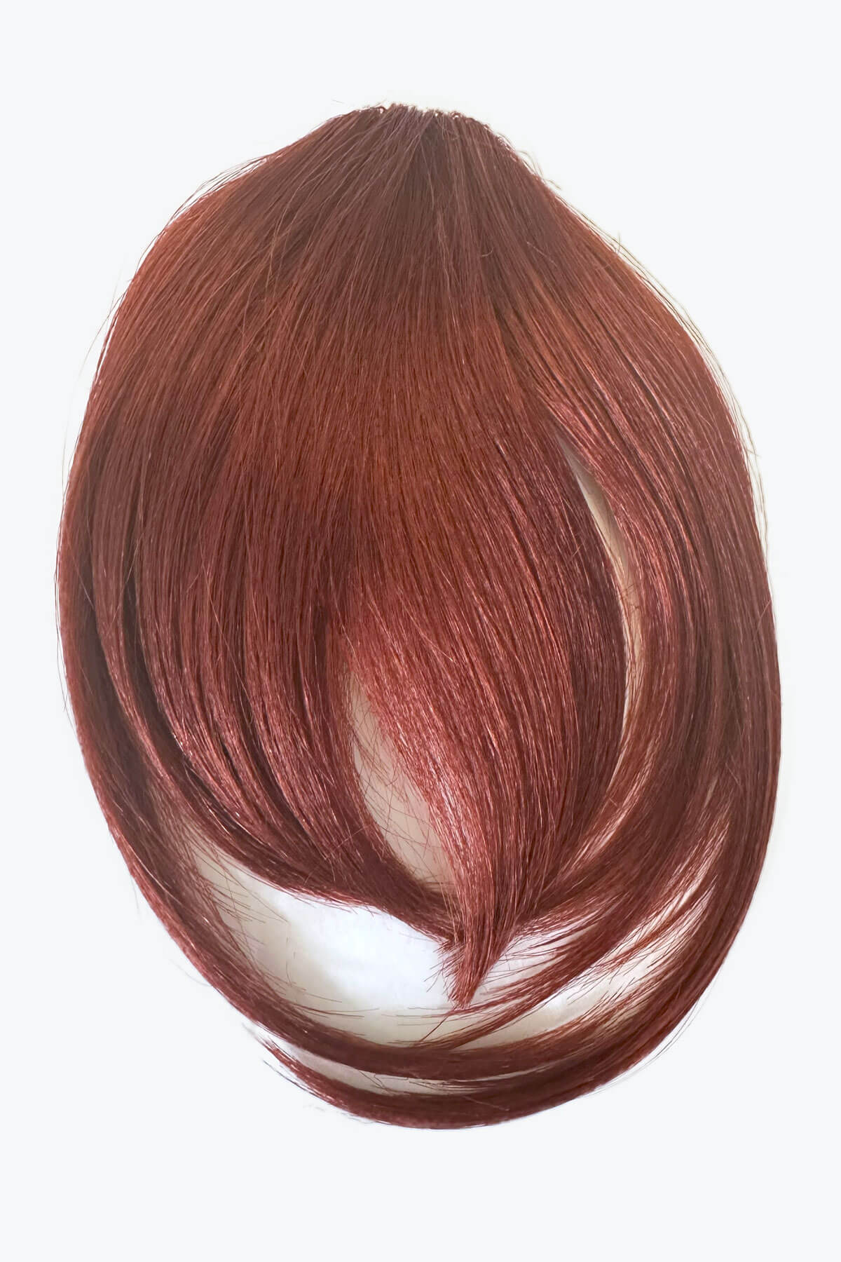 Brown hair extension on a white background. Clip in fringe hairpiece/clip-in bangs, gently feathered with face framing whisps: Delia copper red 130