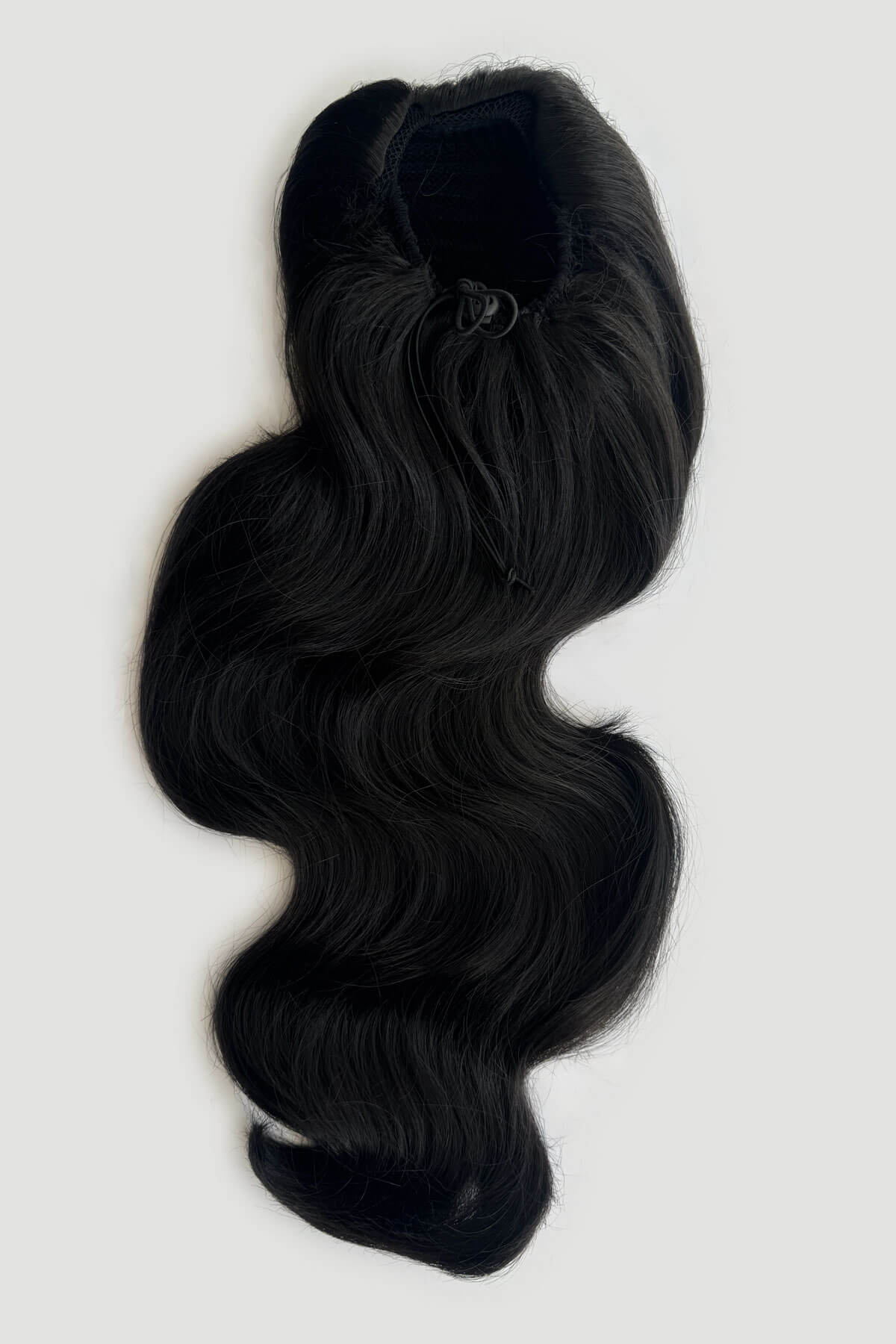 Black wavy hair extension hair piece with draw string attachment, displayed against a light grey background. Double volume hairpiece extension: Naomi black 1B