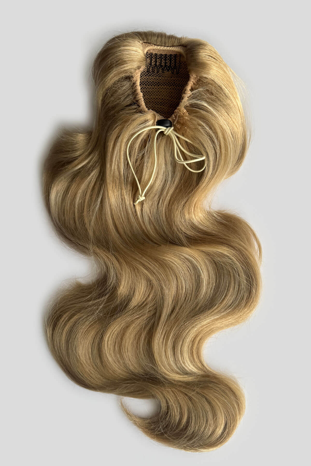 A wavy, shoulder-length blonde hair piece with draw string attachment, displayed against a light background. Double volume hairpiece extension: Naomi blonde 24H613