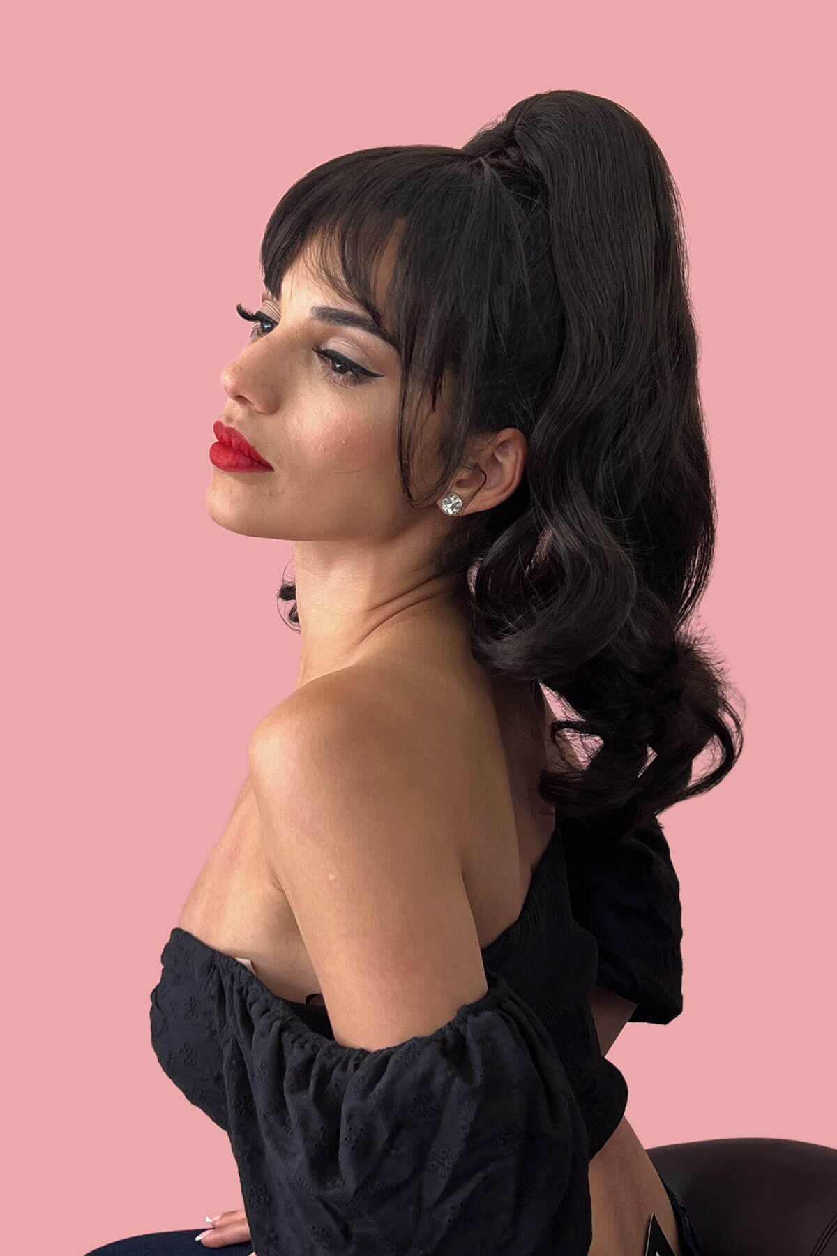 Woman with styled hair and red lipstick against a pink background. Clip in fringe hairpiece/clip-in bangs, gently feathered with face framing whisps: Delia copper red 130