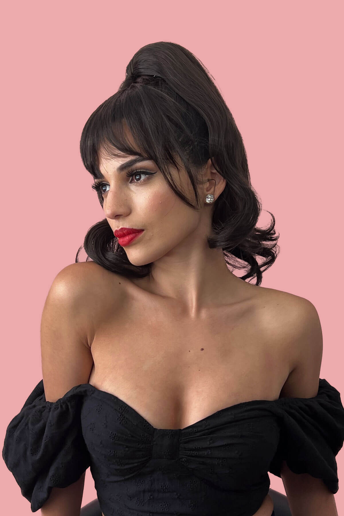 Woman wearing a black off-shoulder top against a pink background. Clip in fringe hairpiece/clip-in bangs, gently feathered with face framing whisps: Delia dark brown 6