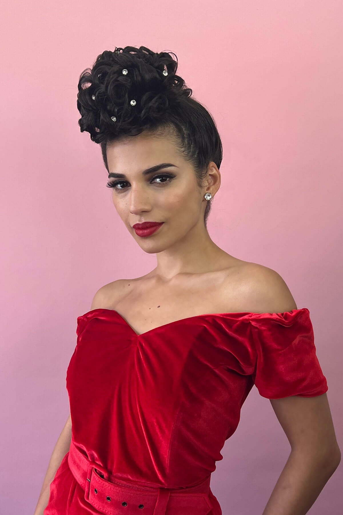 Woman with a hair poodle in a red off-shoulder dress with a pink background. Hair poodle clip-in hairpiece bun vintage style 1950s: Lucille dark chocolate brown 6