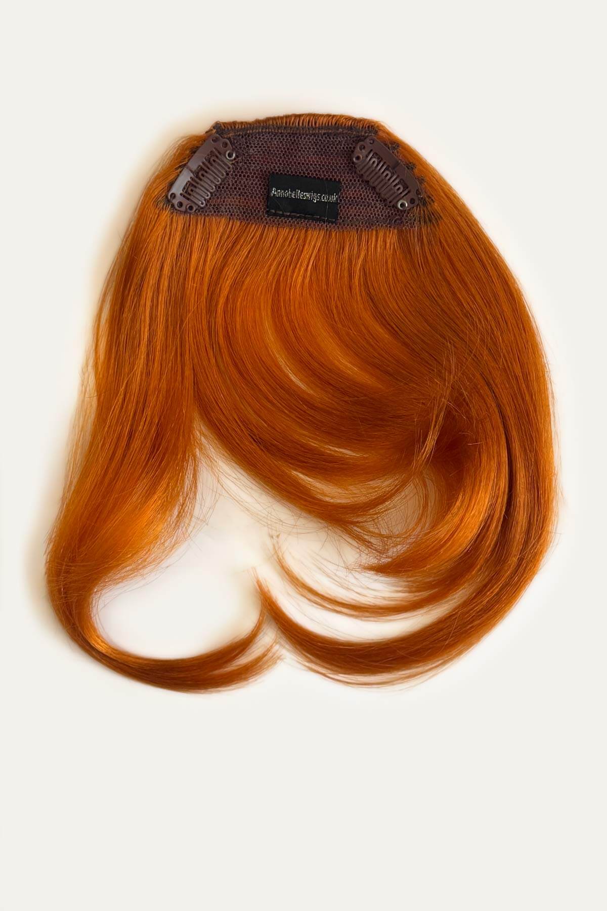 Ginger hair extension on a white background. Clip in fringe hairpiece/clip-in curtain bangs, with long, face framing wisps: Sabrina