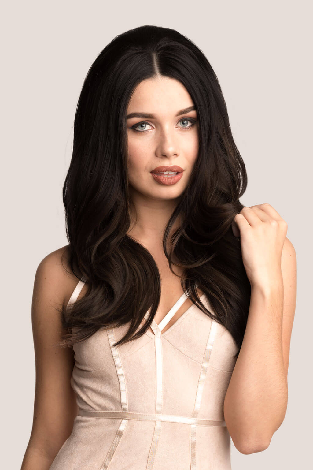 Woman with long, dark hair wearing a beige dress against a light background. Volume and Height Booster Hairpiece: Blaise - champagne blonde 613