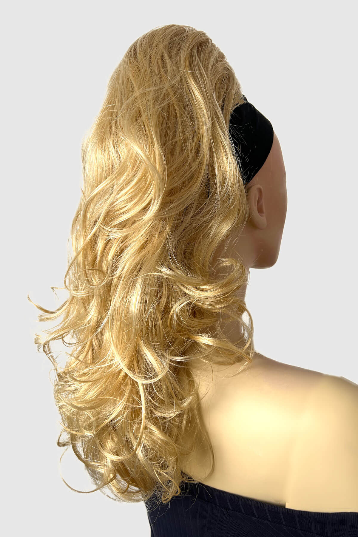 A woman wearing a floral off-shoulder top with a curly ponytail hairpiece extension in dark brown color. blonde LG26