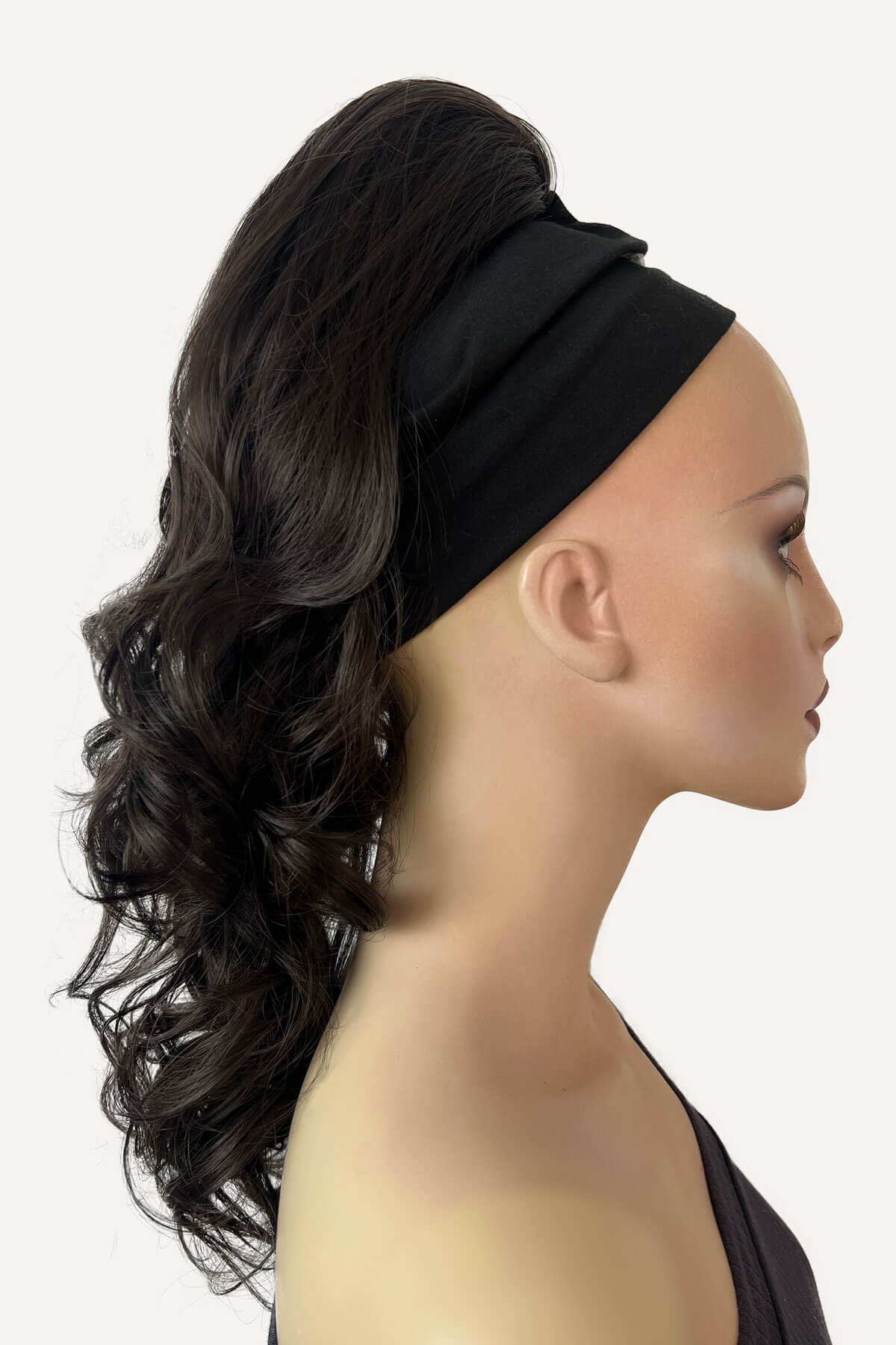 A woman wearing a floral off-shoulder top with a curly ponytail hairpiece extension in dark brown colour. Curly ponytail hairpiece extension: Katy dark brown 4