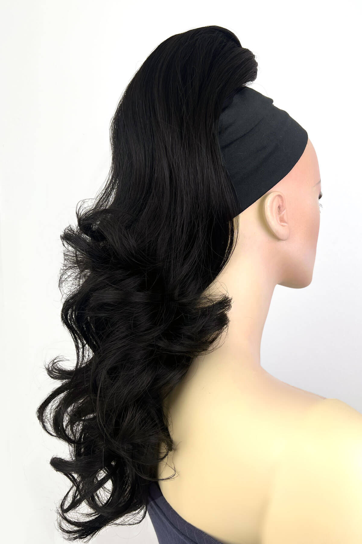 Black hairpiece styled on a mannequin head against a white background. Wavy, long ponytail hairpiece extension: Casey black 1b