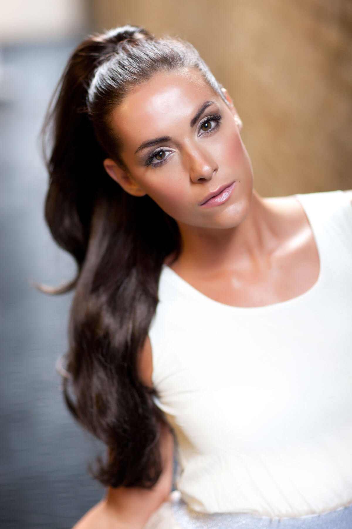 Woman with long dark hair styled in a half-up, half-down style against a blurred background. Clip-in ponytail hair piece extension, flexihair: Poppy black 1b