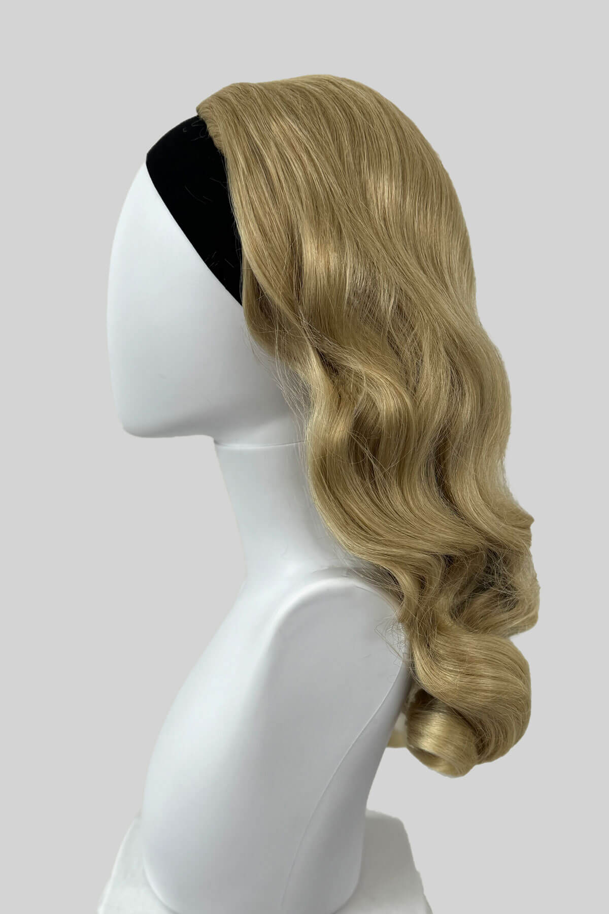 Blonde wig on a mannequin head against a white background. 1950s style half wig hairpiece with beautiful waves: Morgana blonde 613T24