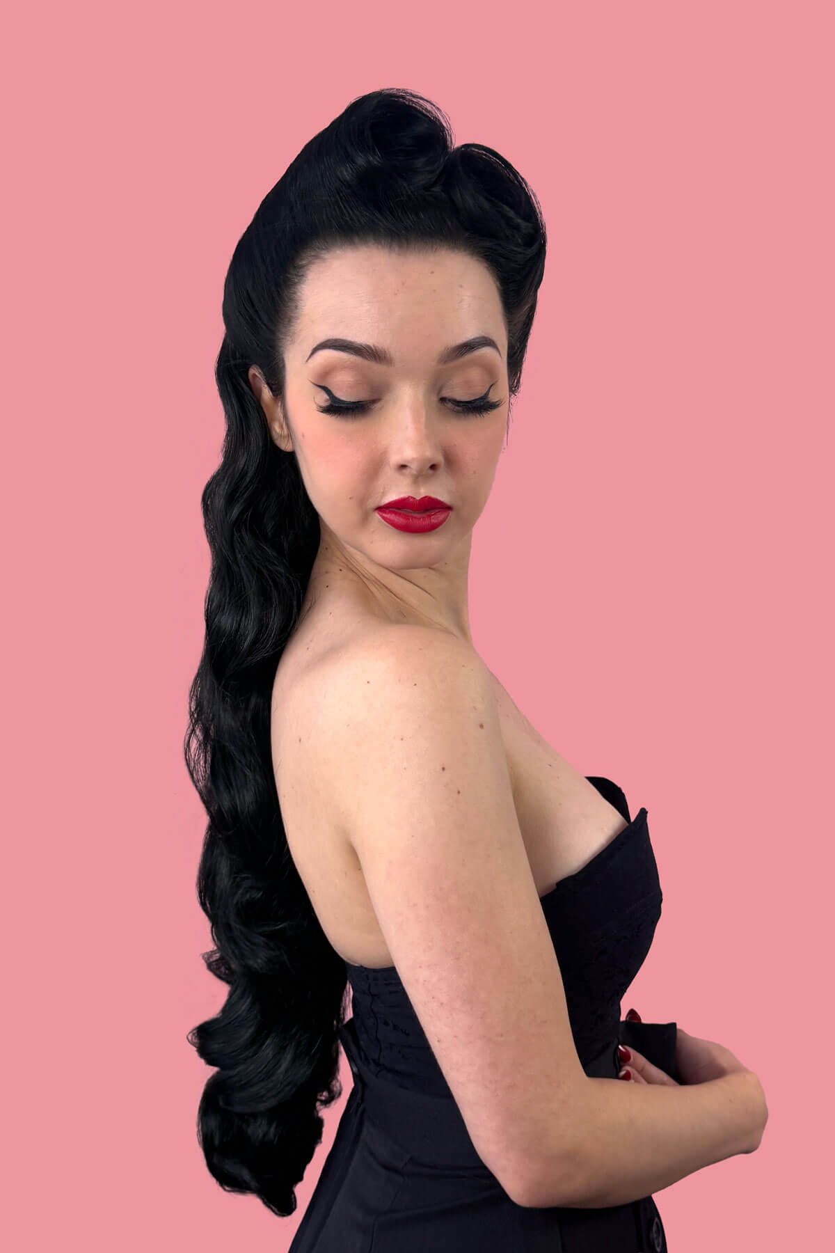 Woman with long, wavy black hair on a pink background. Ultra long half wig with hollywood waves. black 1B
