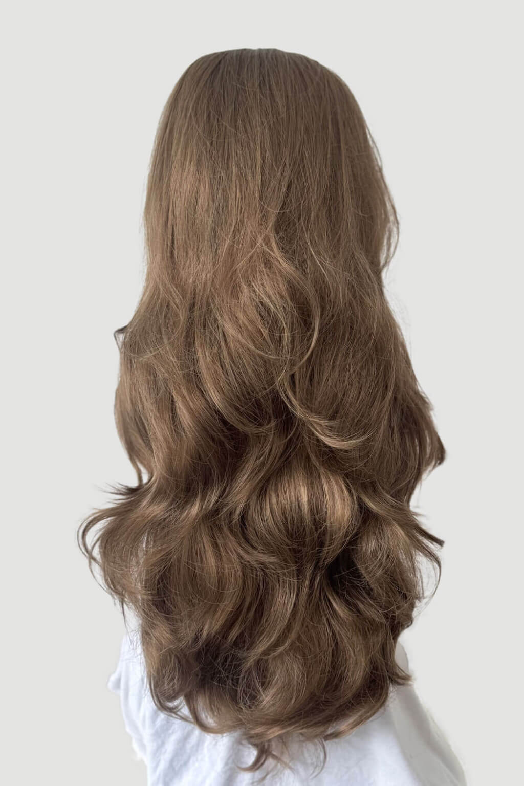 Long, wavy brown hair extension on a plain background. High crown long, wavy half wig and volume ring: Bardot brown 10-16-27
