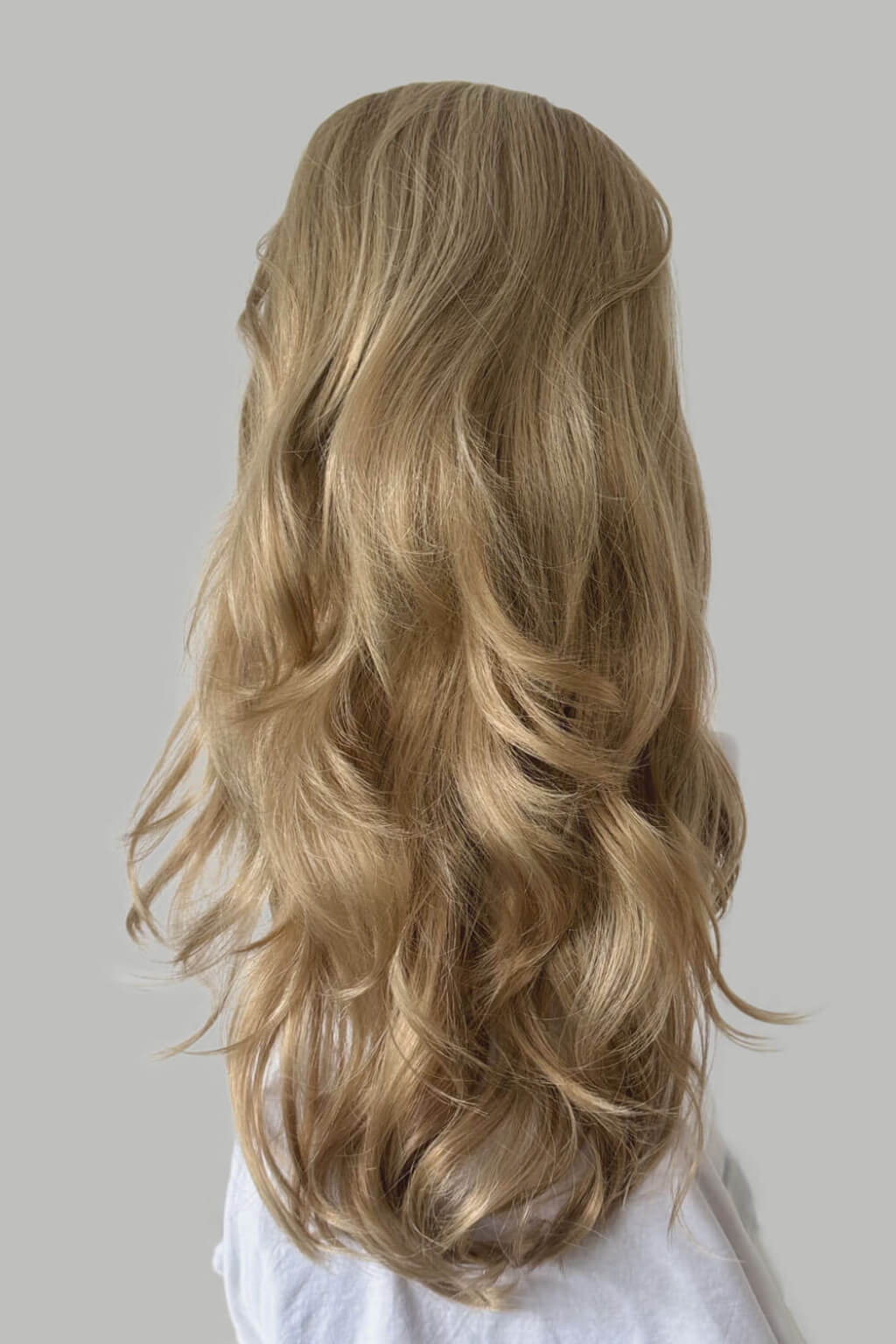 A long, wavy blonde wig displayed on a white mannequin head against a grey background. High crown long, wavy half wig and volume ring: Bardot blonde 24H613
