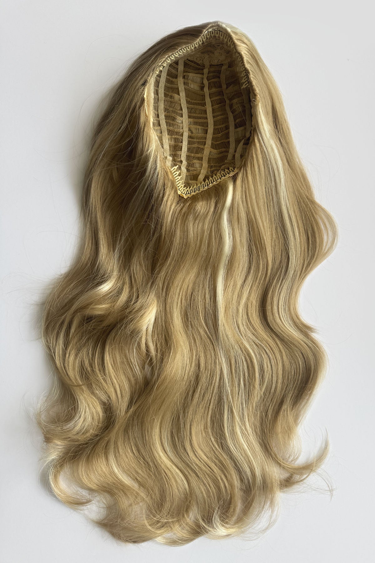 A long wavy synthetic wig with blonde and brown ombre highlights, displayed against a light background. Corrine - Bouncy Blowout style with Volume Booster Half Wig blonde 24H613
