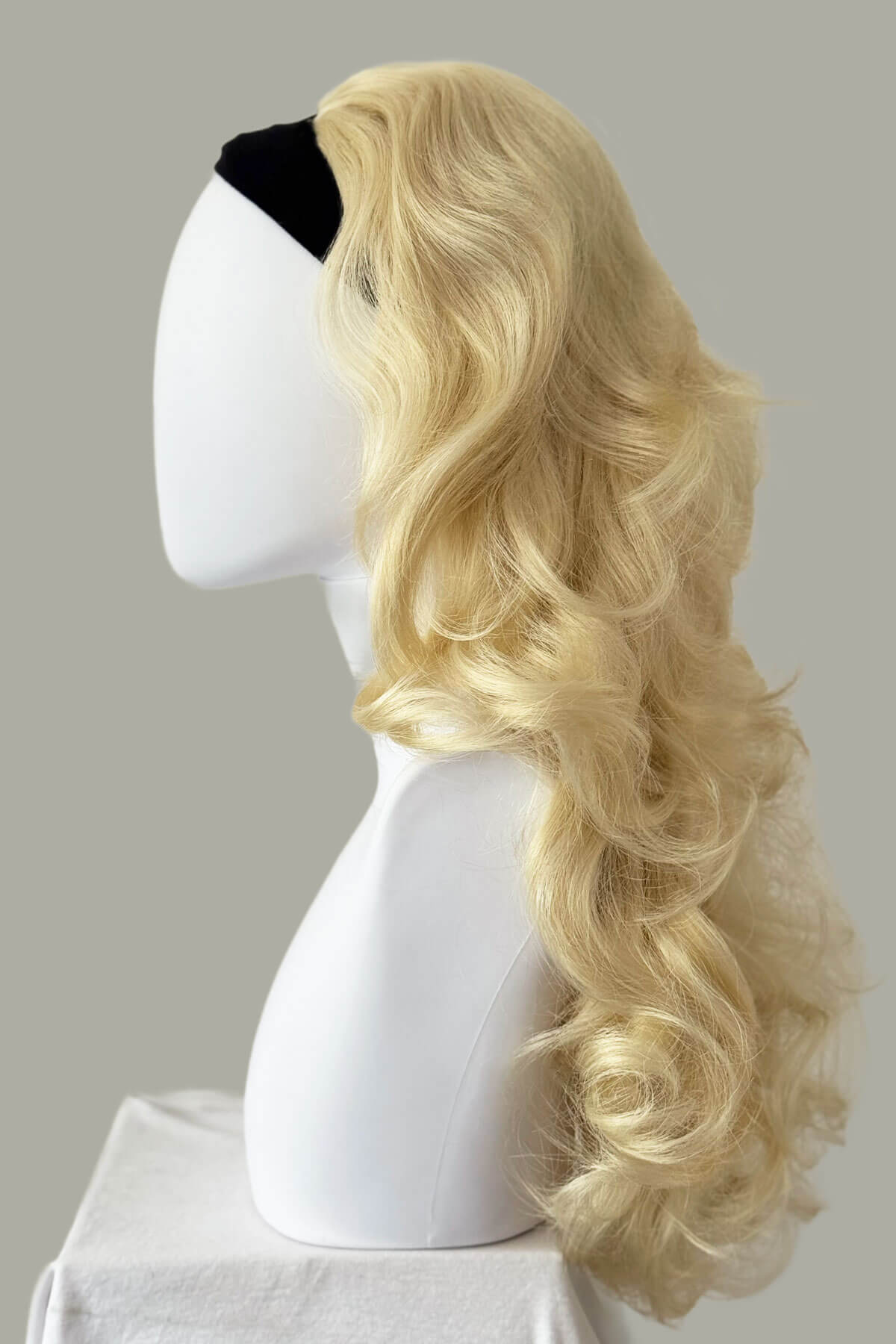 Blonde wig on a mannequin head against a plain background. Curly blonde half wig hairpiece extension (3/4 wig), long: Meana champagne blonde 613