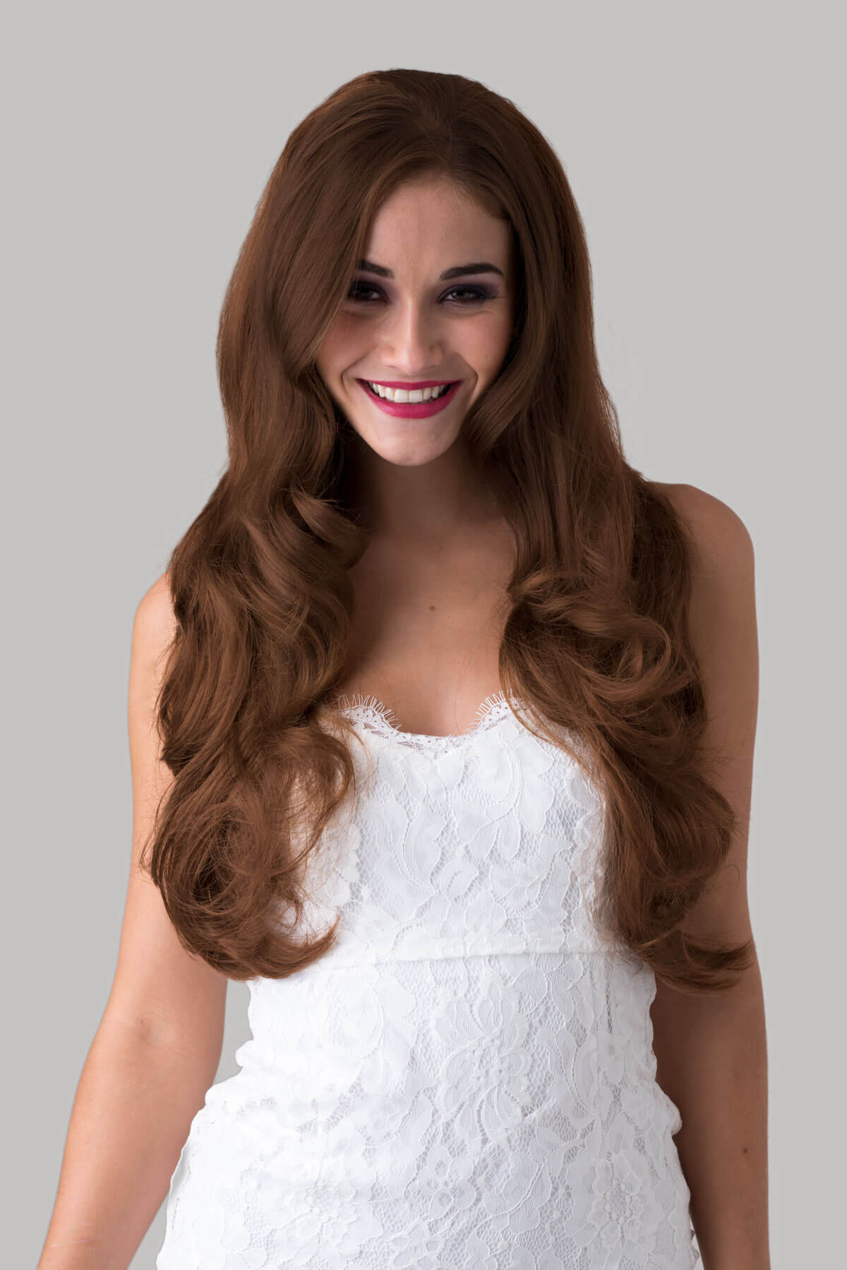 Woman with long brown wig wearing a white dress on a gray background. Auburn half wig hairpiece, long and wavy: Lyndsey