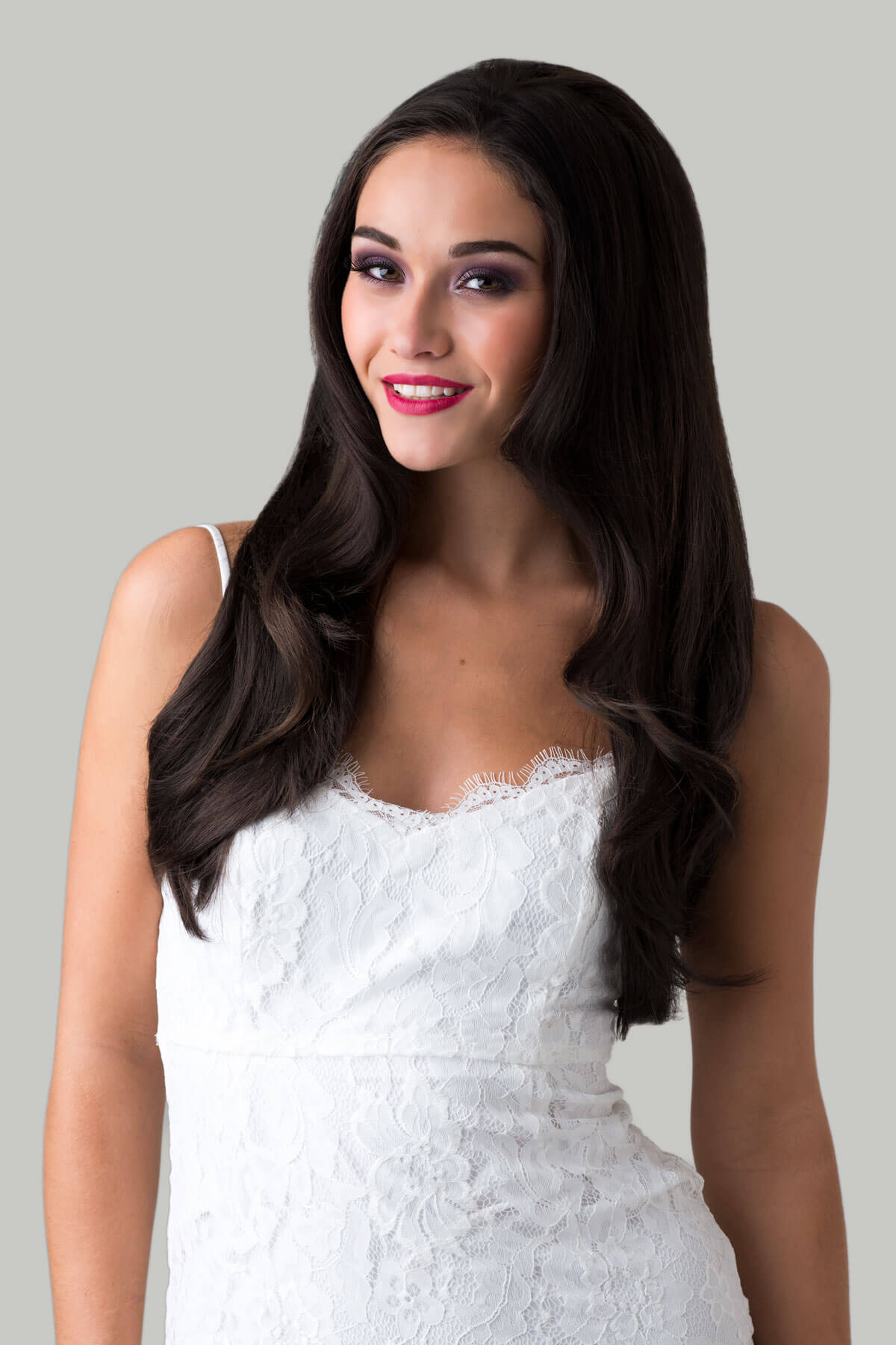 A woman wearing a brown half wig hairpiece with straight layers. She is smiling and wearing a white top. Brown half wig hairpiece, layered and straight: Summer dark chocolate brown 6