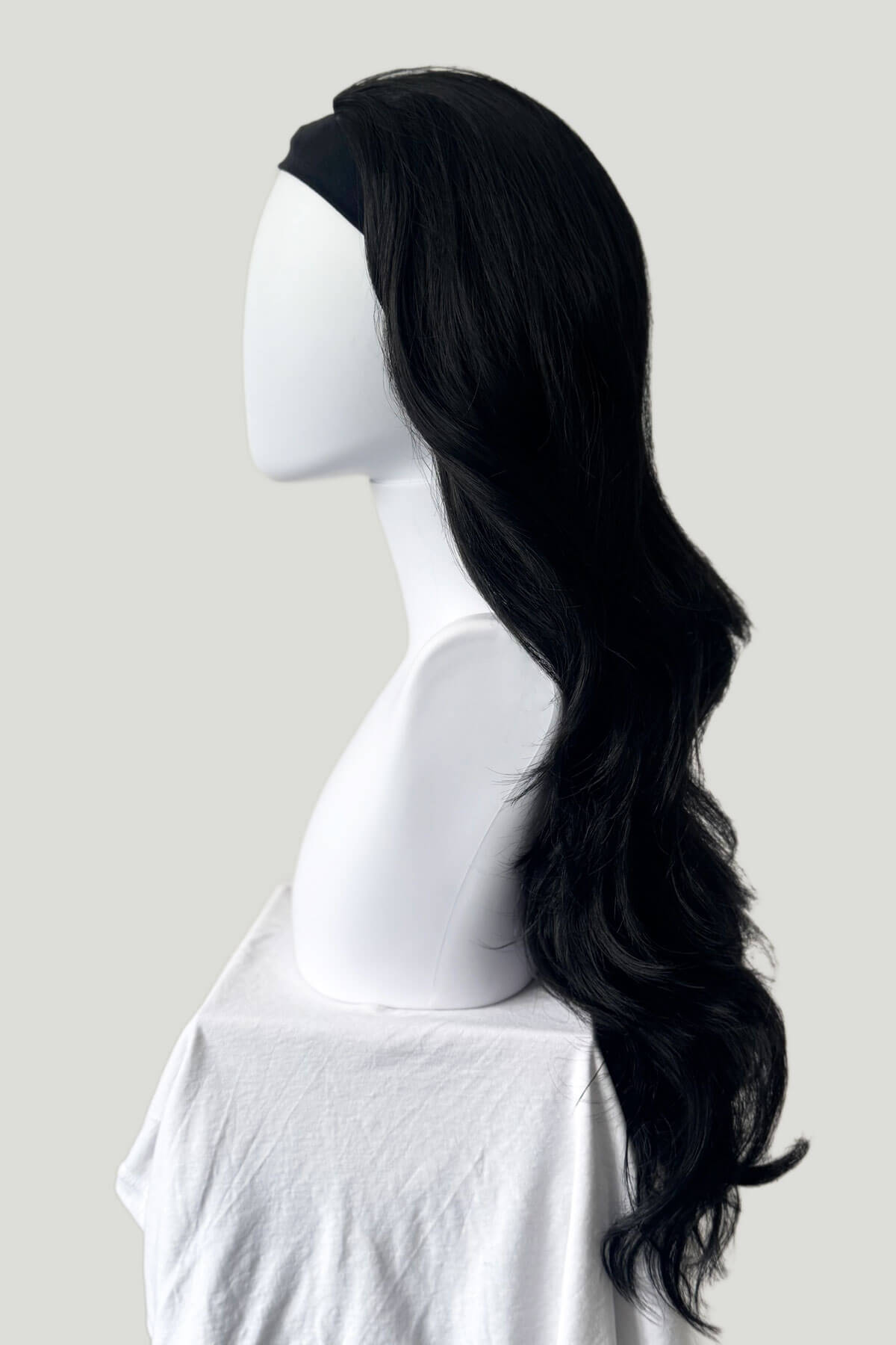 Black wig on a mannequin head against a plain background.  Black 3/4 hairpiece (half wig) with long waves: Jessie black 1b