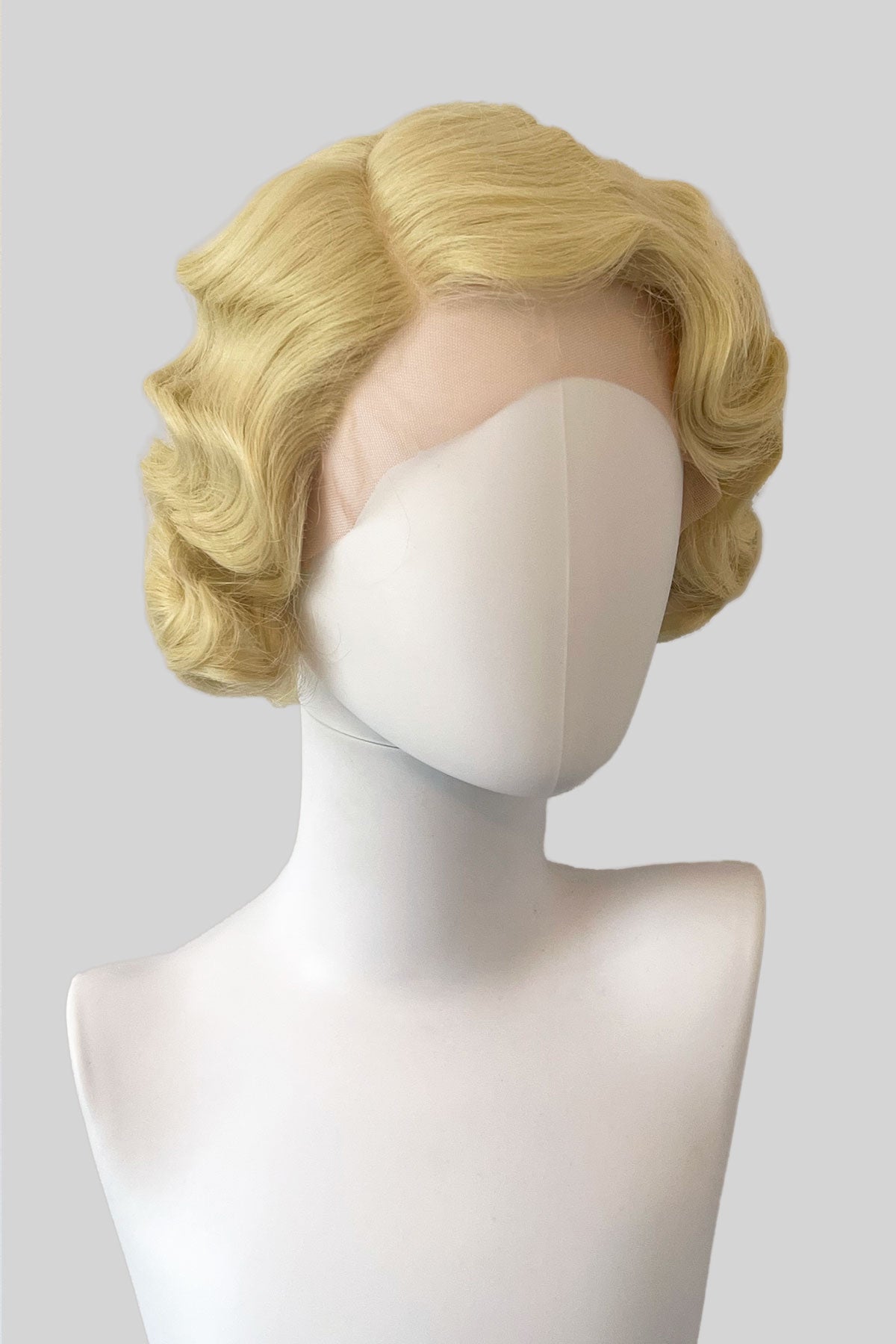 Blonde wig on a mannequin head against a plain background.  Blonde pinup wig, lace front, vintage style: Odette blonde 613