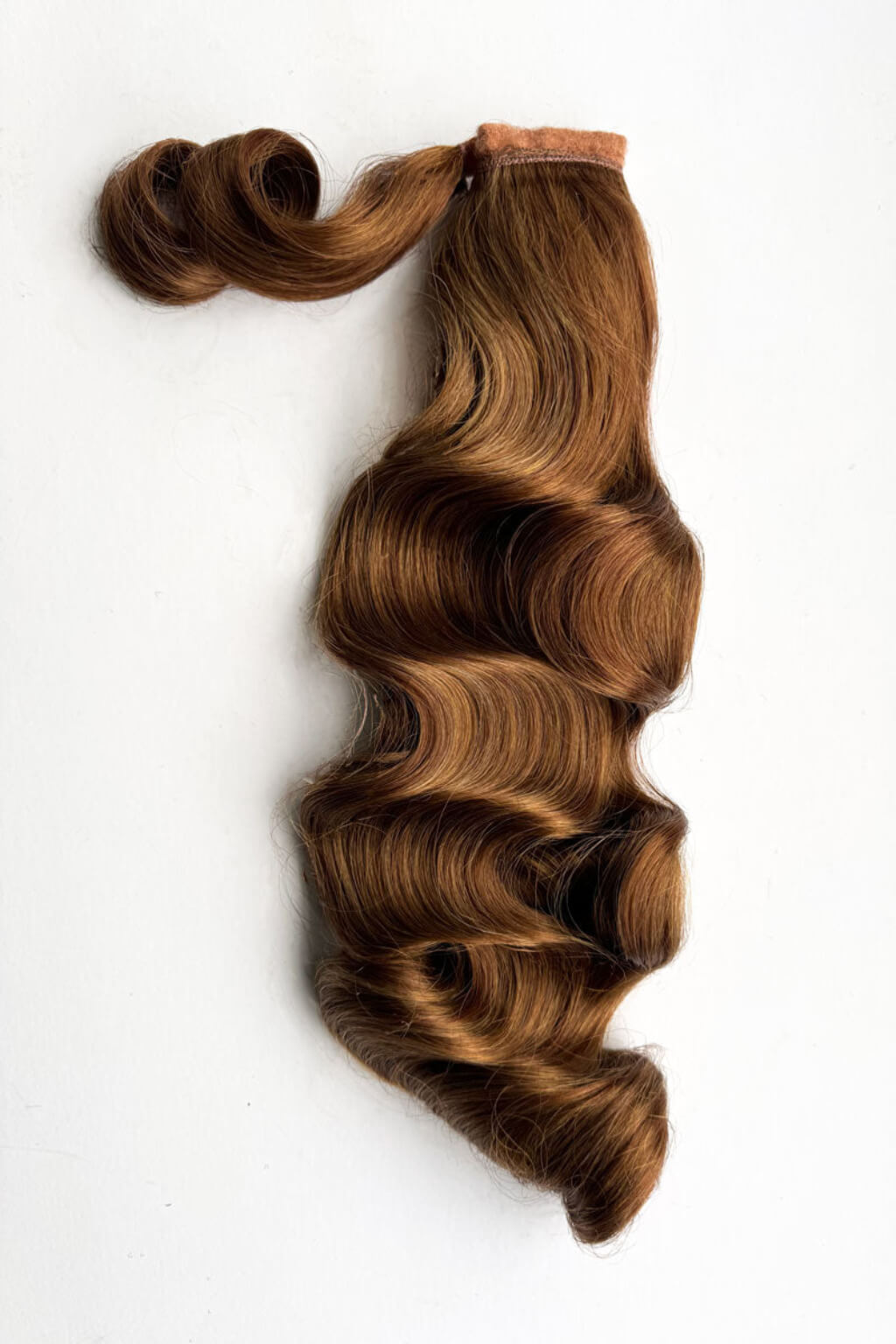 Brown hair extensions with a white background. Retro style ponytail hairpiece, long with vintage waves: Arabella Brown 27C29