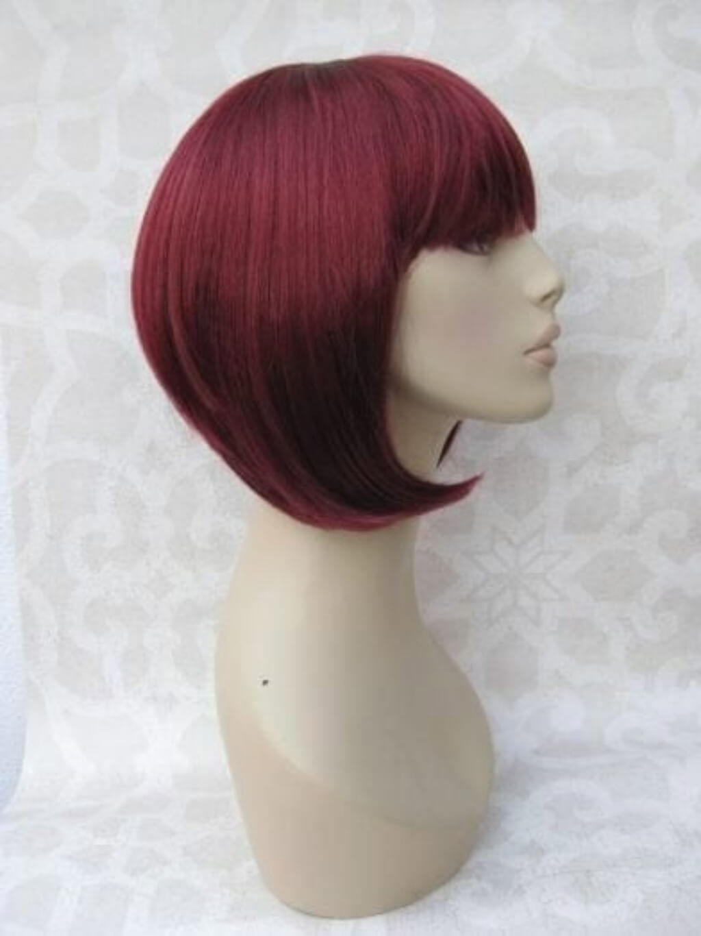 Red wig on a mannequin head against a white background. Red inverted bob wig, short and chic: Flavia