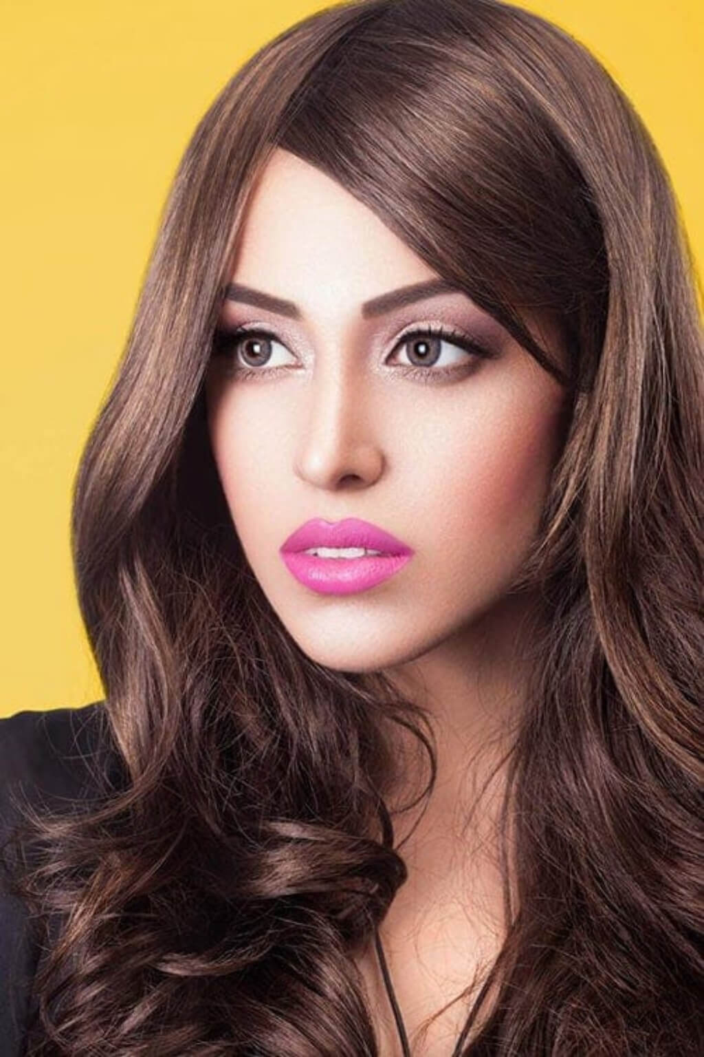 Woman with long brown hair and pink lipstick against a yellow background. Annabelle's Wigs synthetic wig Long brown wig with gentle waves: Bella