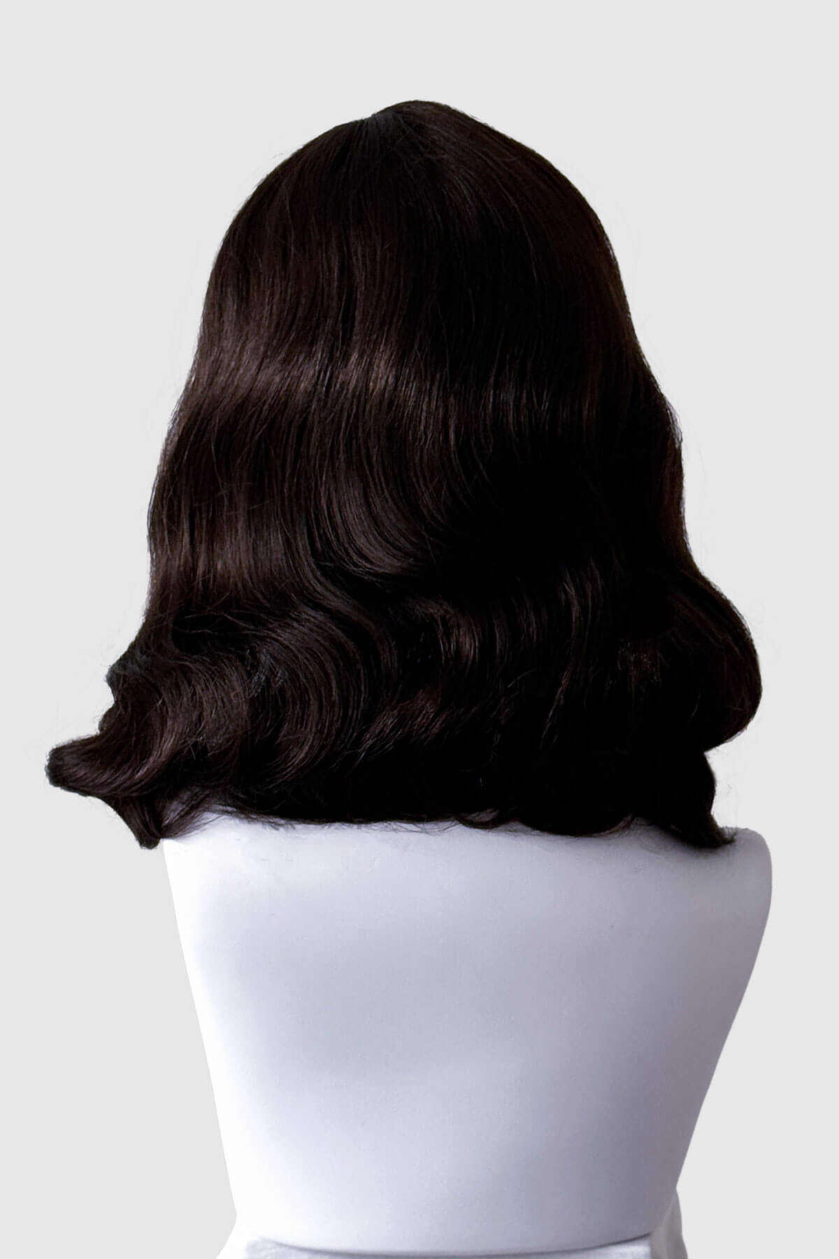Dark brown wig on a mannequin head against a white background. Dark brown pinup style wig, finger waved with short fringe, 1950s style: Becca