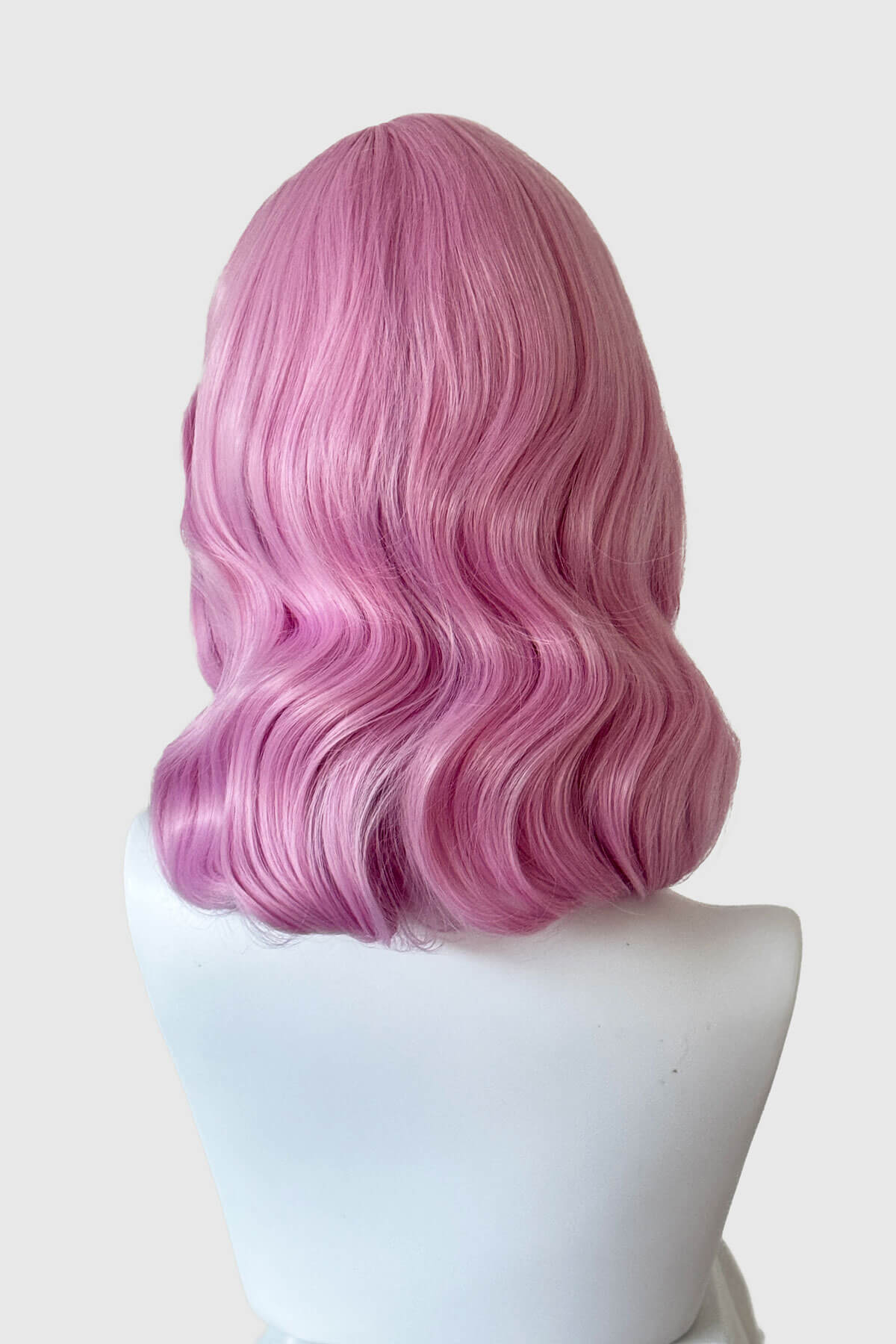 Pink wig on a mannequin head against a white background. Pink pinup style wig, with finger waves and a short fringe, 1950s style: Stevie light pink 2614