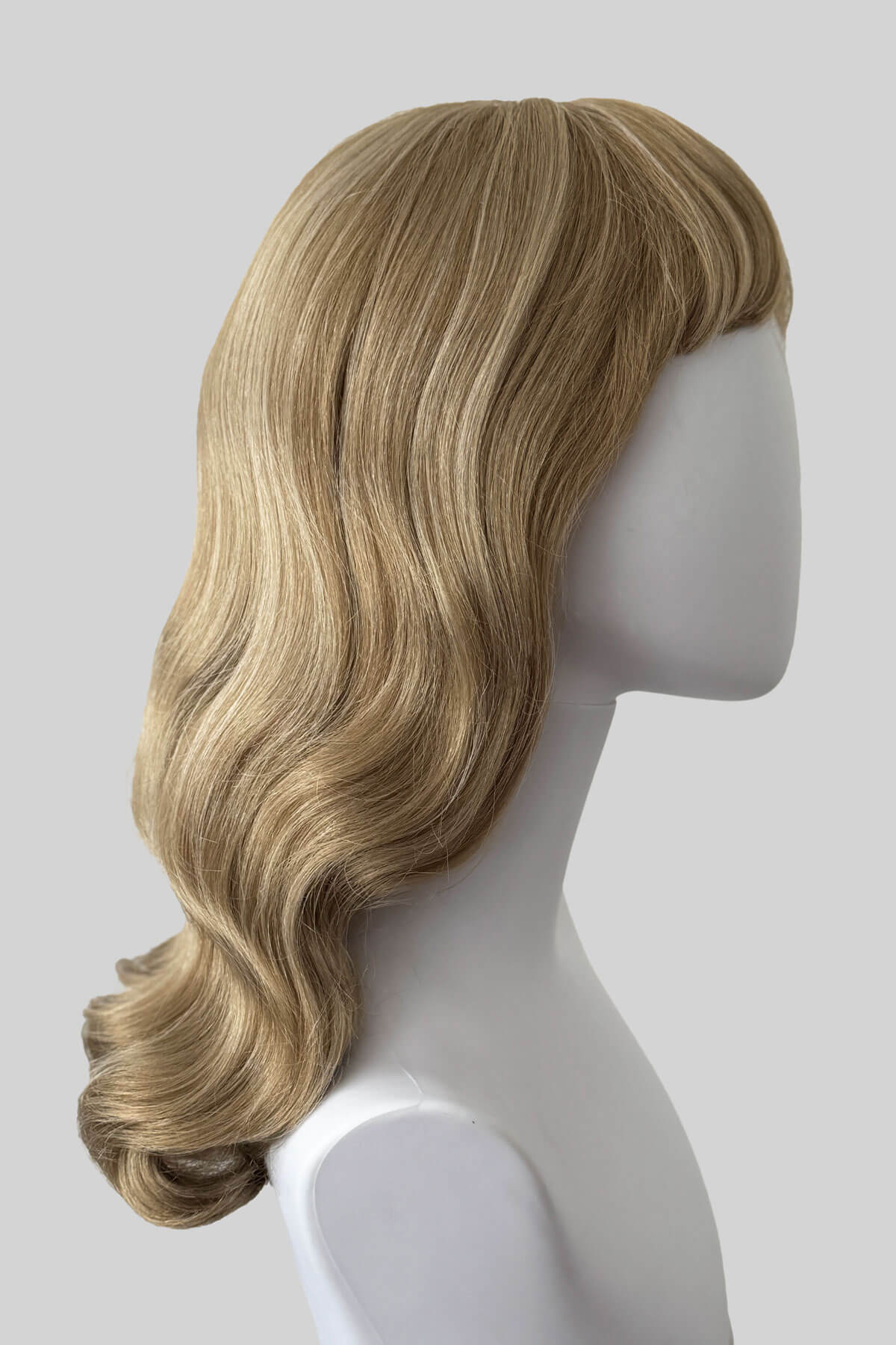 Blonde wig on a mannequin head against a plain background. Long blonde pin-up wig, old Hollywood waves with short fringe: Emmeline