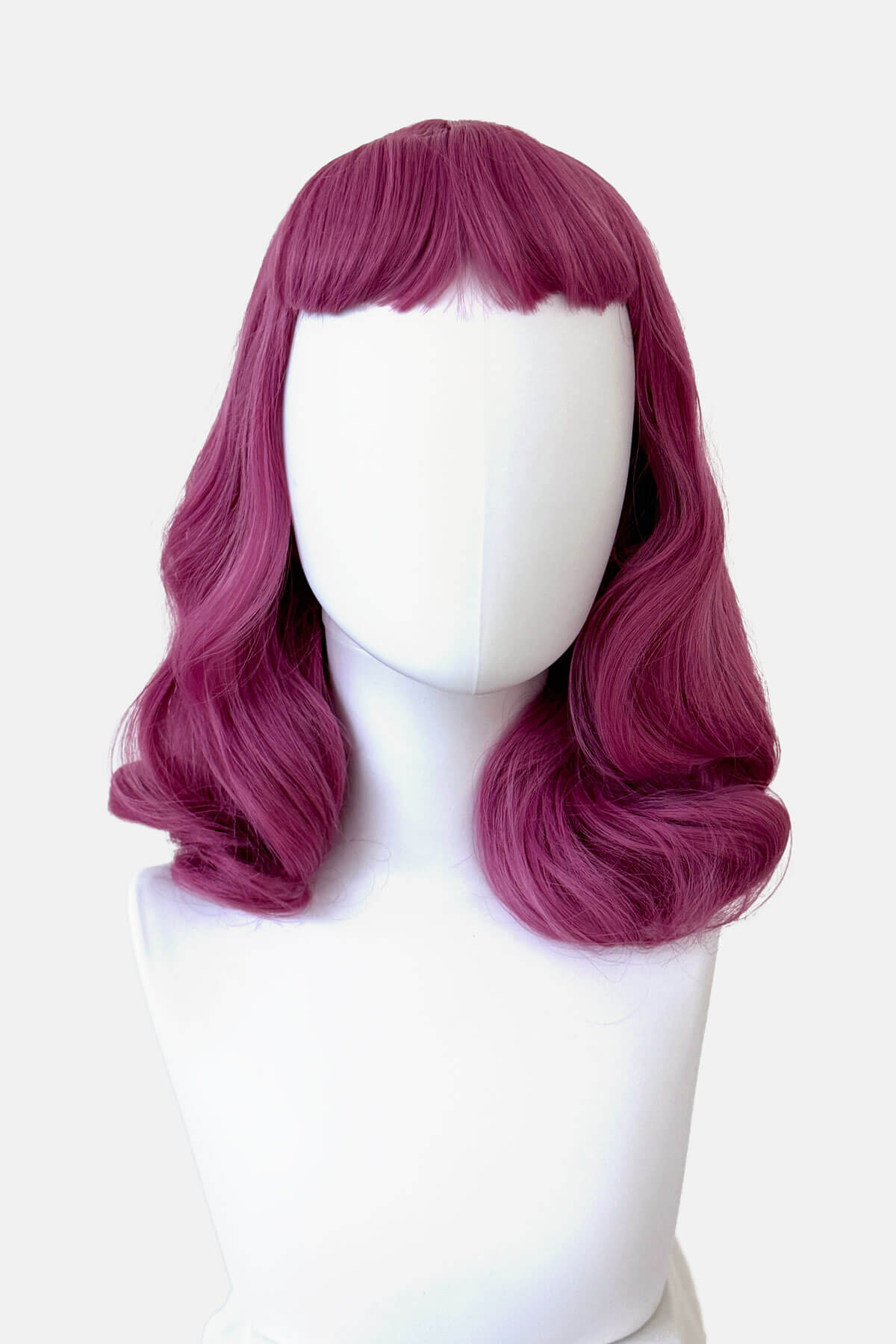 Purple wig on a white mannequin head against a white background. Pink pinup style wig, with finger waves and a short fringe, 1950s style: Stevie 2520J