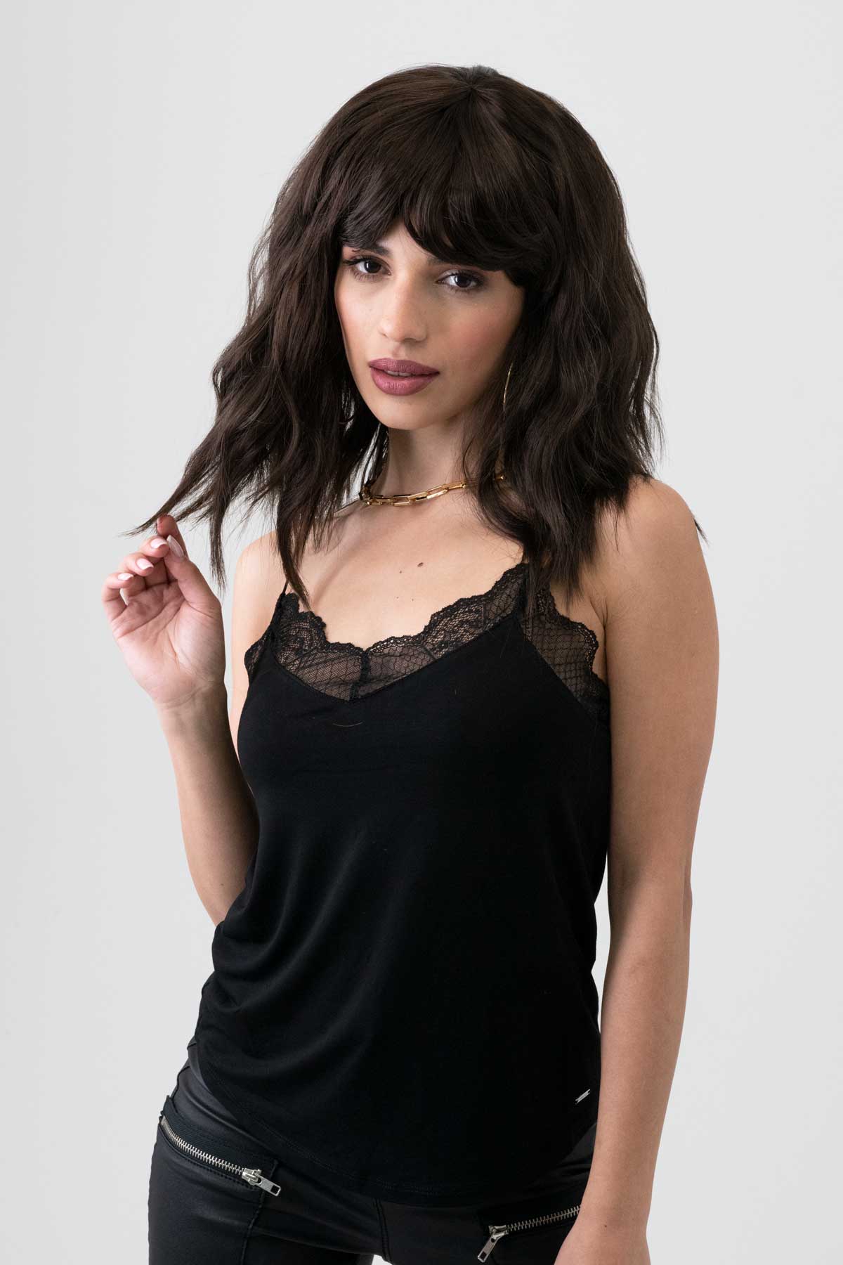 Woman wearing a black lace top against a plain background. Dark chocolate brown long wavy bob wig: Roxy