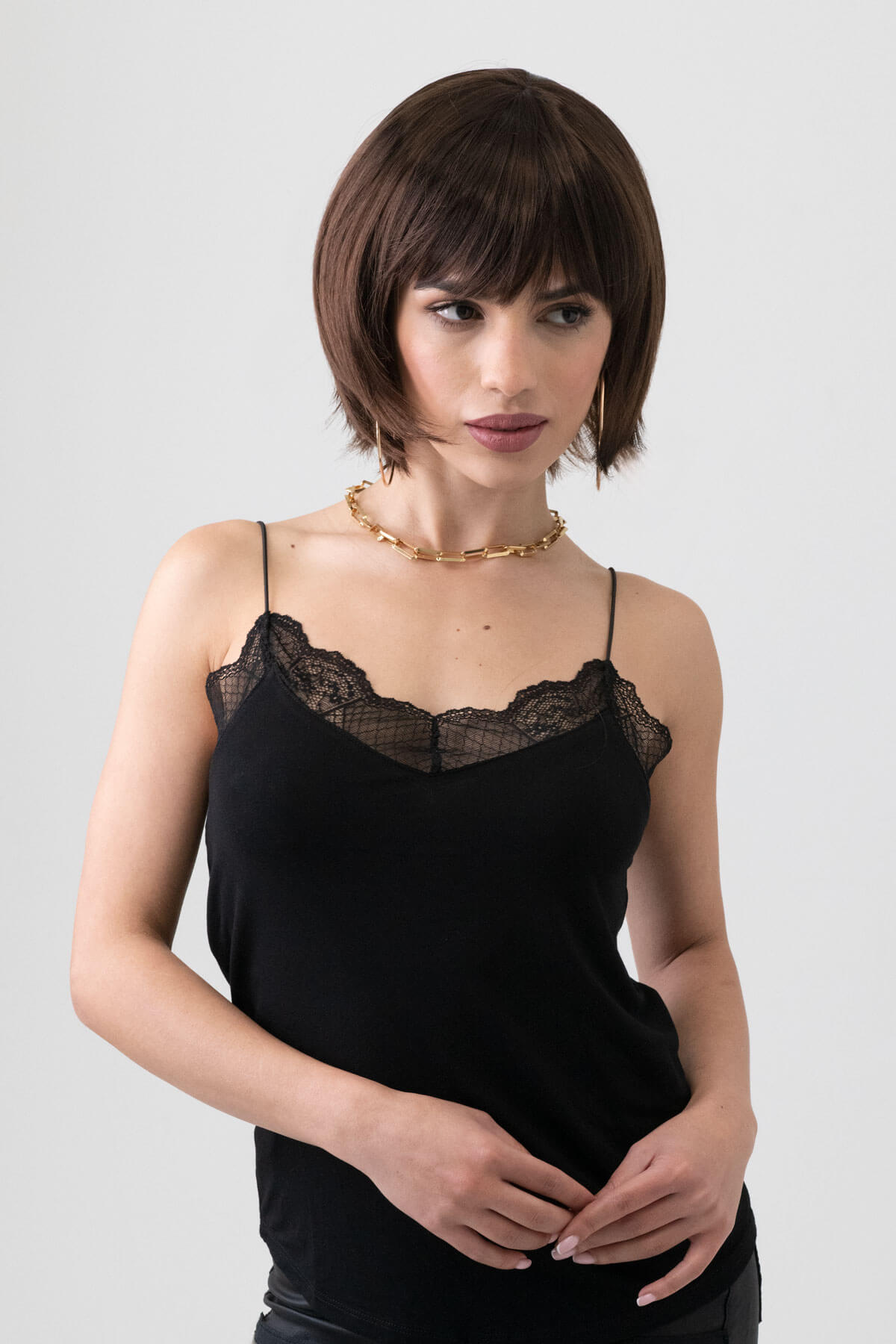 Woman wearing a black lace camisole against a plain background. Dark brown pixie cut wig with reddish brown lowlights: Cierra