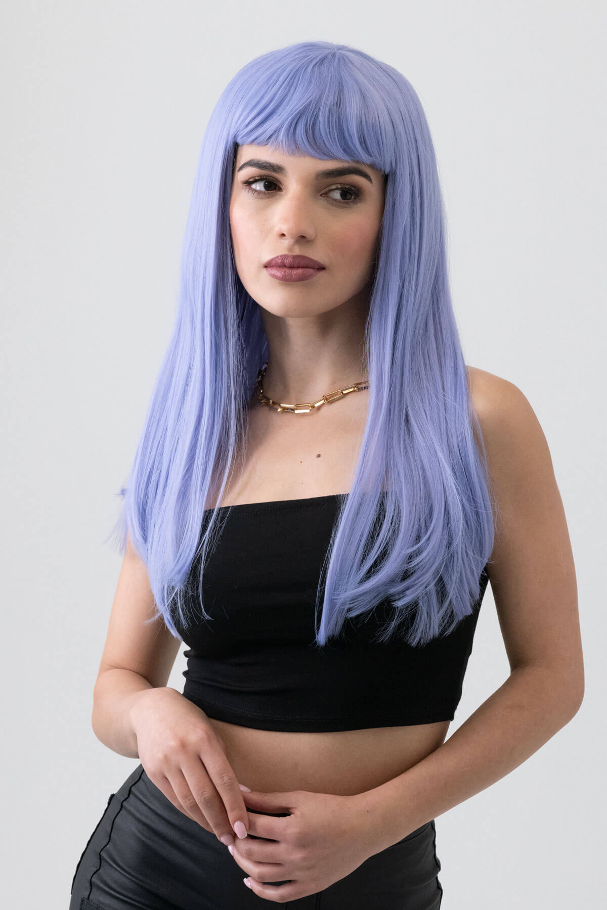 Woman with a long blue wig wearing a black top against a plain background. Long blue wig with short, straight fringe: Alyssa