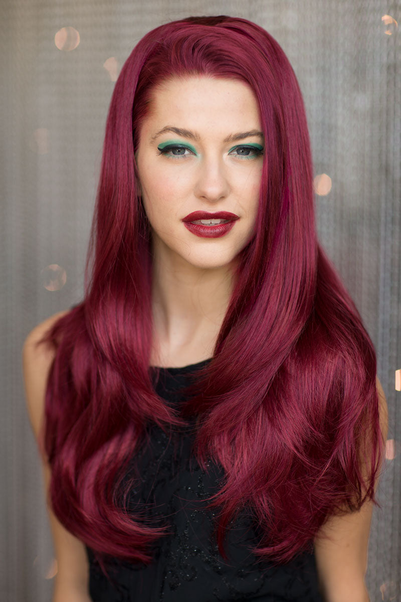 A woman wearing a straight red half wig hairpiece extension, with the wig appearing voluminous and long.